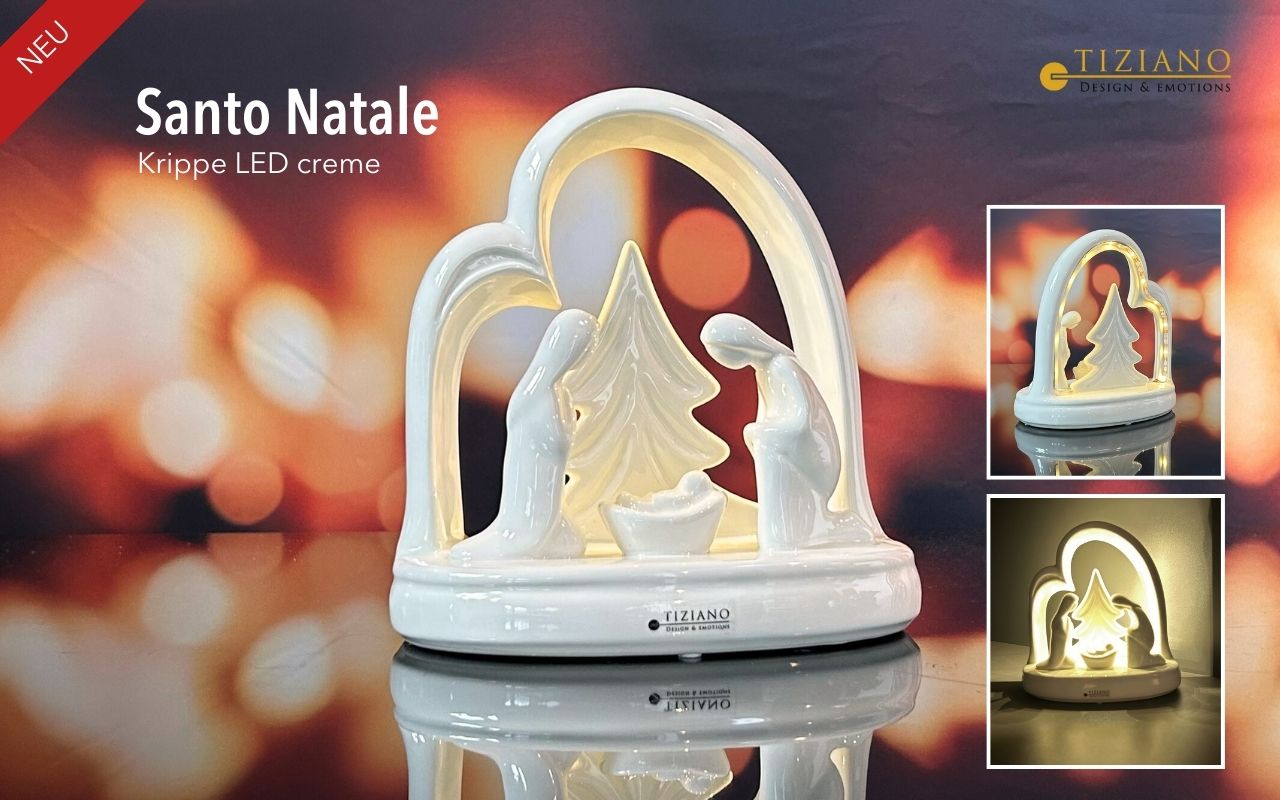 Eine cremefarbene Tiziano-Krippenfigur aus Keramik mit einem stilisierten Bogen, einem Weihnachtsbaum und der Heiligen Familie, beleuchtet durch integrierte LED-Lichter vor einem verschwommenen, warmen, festlichen Hintergrund.