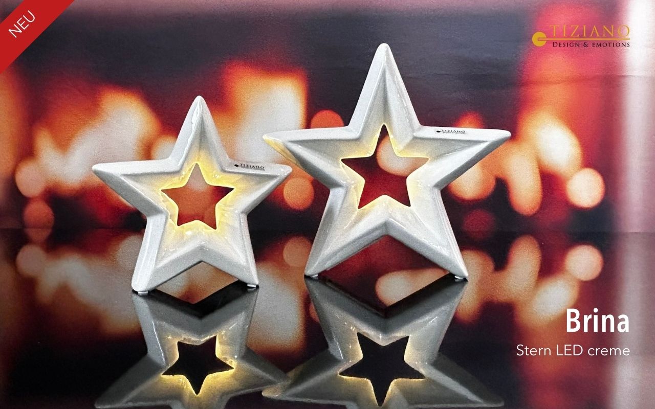Zwei weiße sternförmige LED-Dekoornamente von Tiziano, dargestellt in unterschiedlichen Größen vor einem unscharfen, warm getönten Bokeh-Hintergrund mit reflektierender Oberfläche.