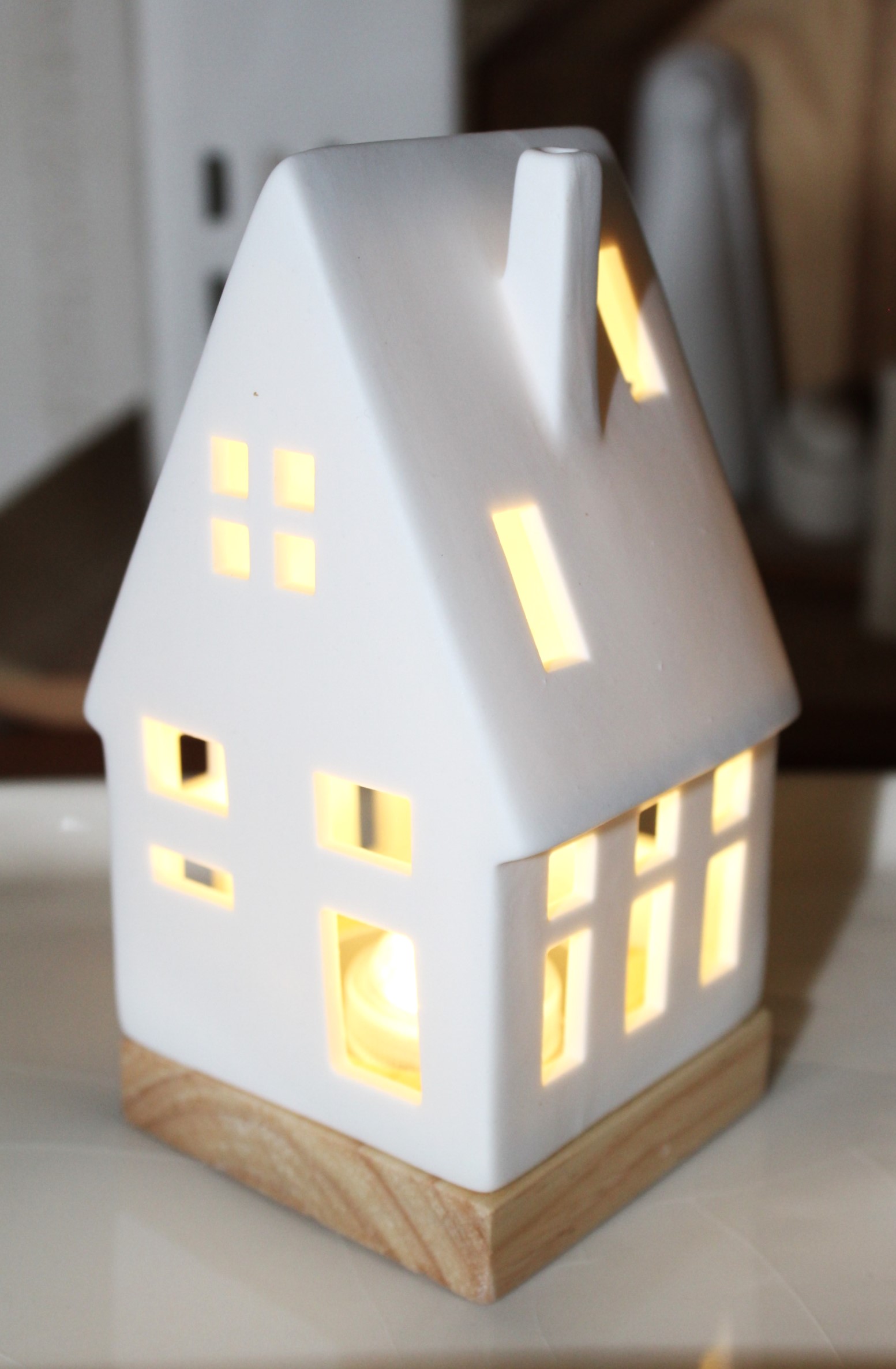 Eleganter Teelichthalter aus weißer Keramik mit warmem Licht aus den Fenstern, perfekt für die Inneneinrichtung und Umgebungsbeleuchtung.