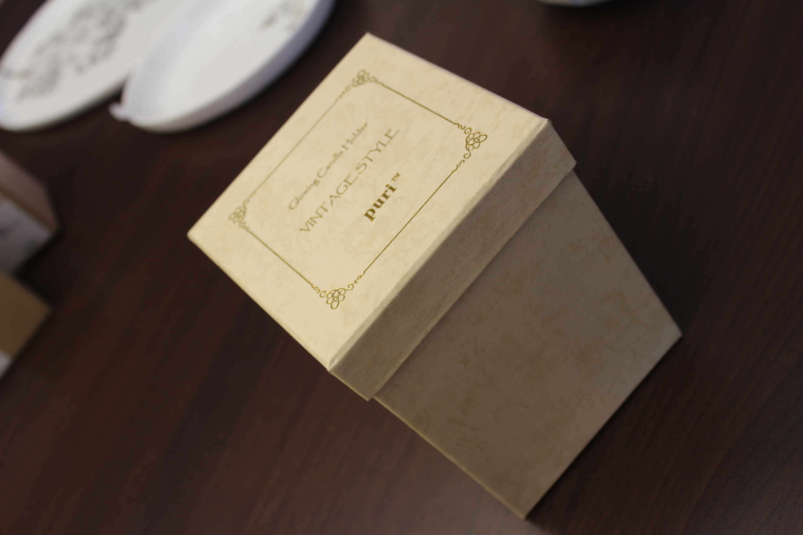 Cremefarbene Geschenkbox im Vintage-Stil auf einem dunklen Holztisch.