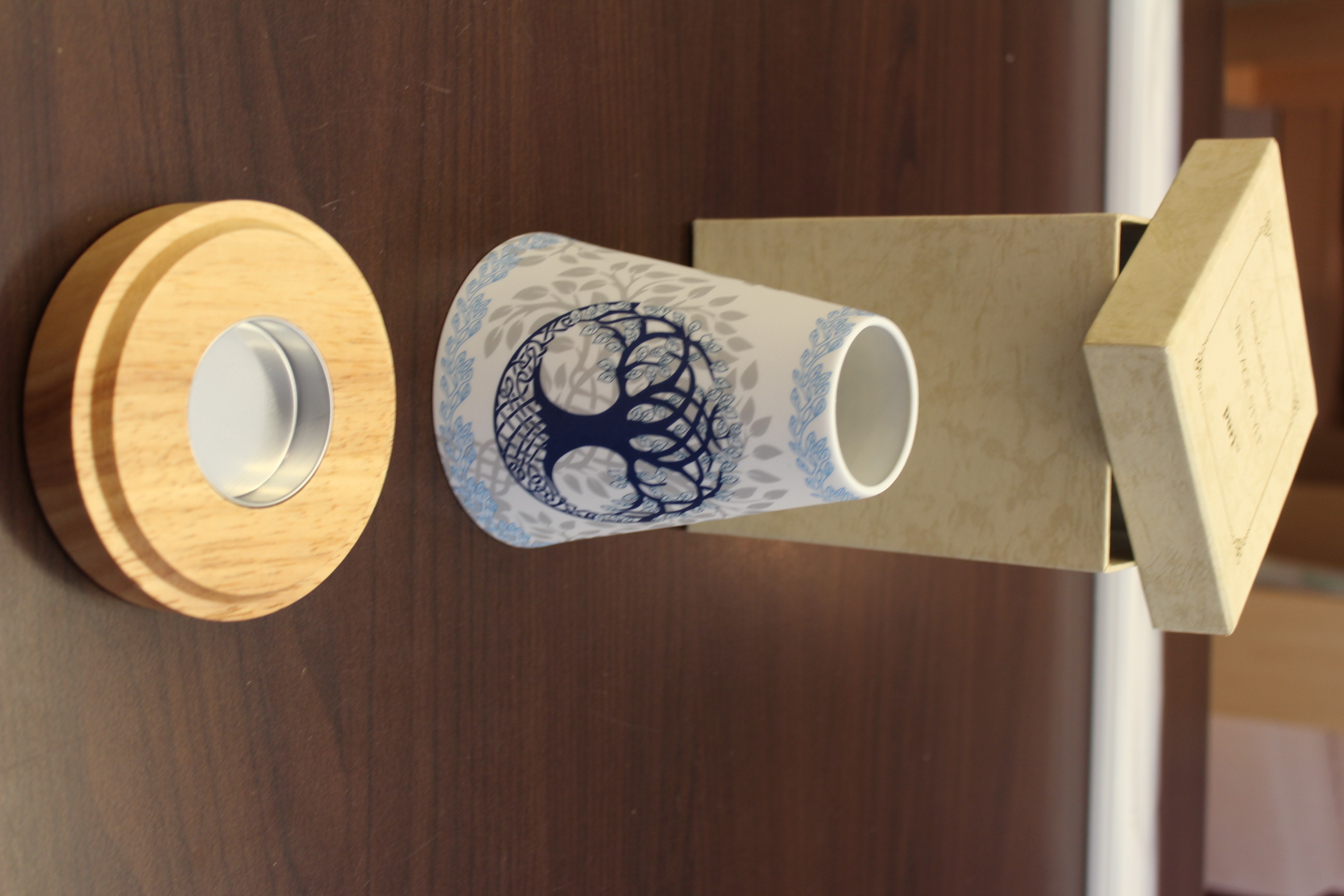 Dekorativer Keramik-Lichtdiffusor mit Baumdesign und Holzsockel auf einem Tisch.