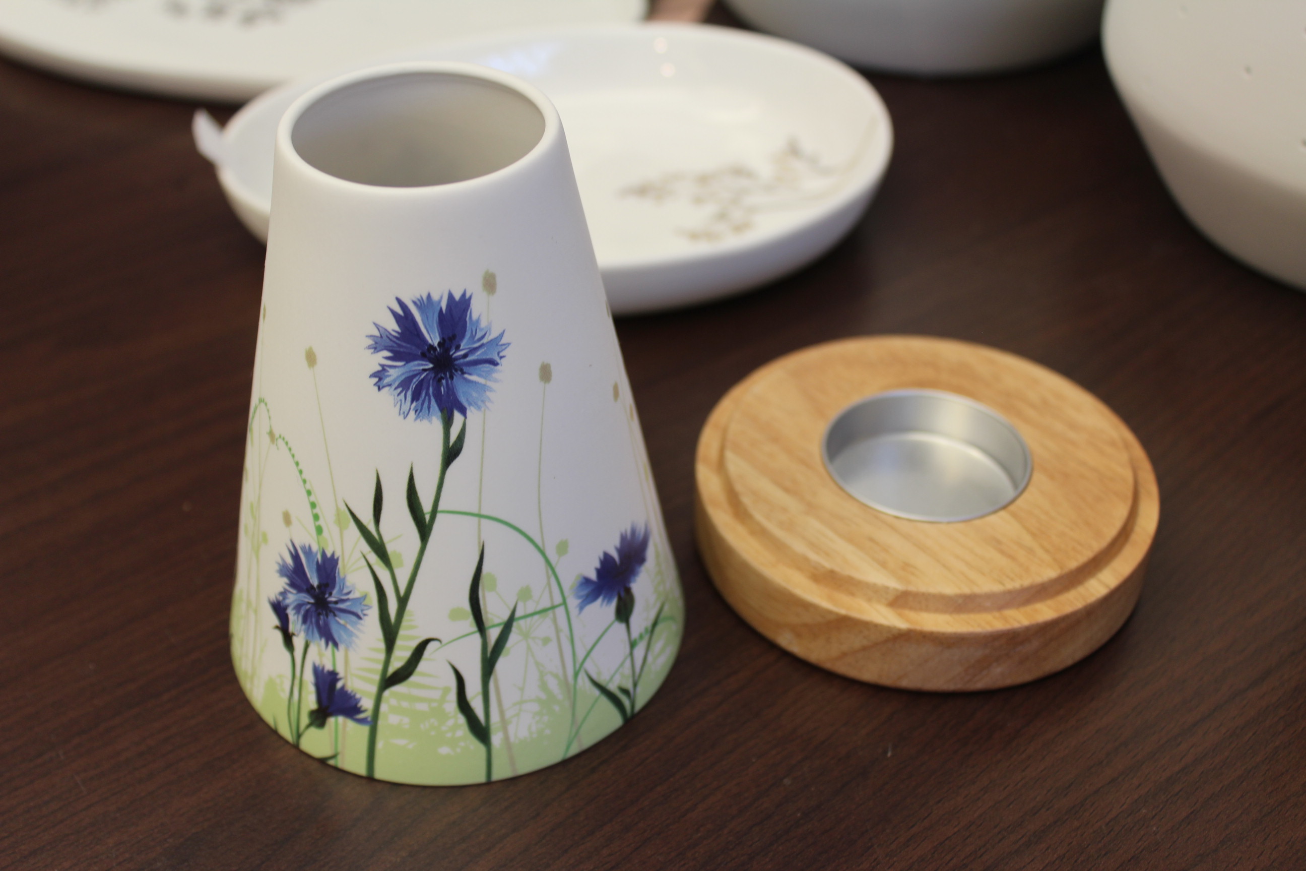 Keramikvase mit blauem Blumenmuster und Holzdeckel auf einem Holztisch.
