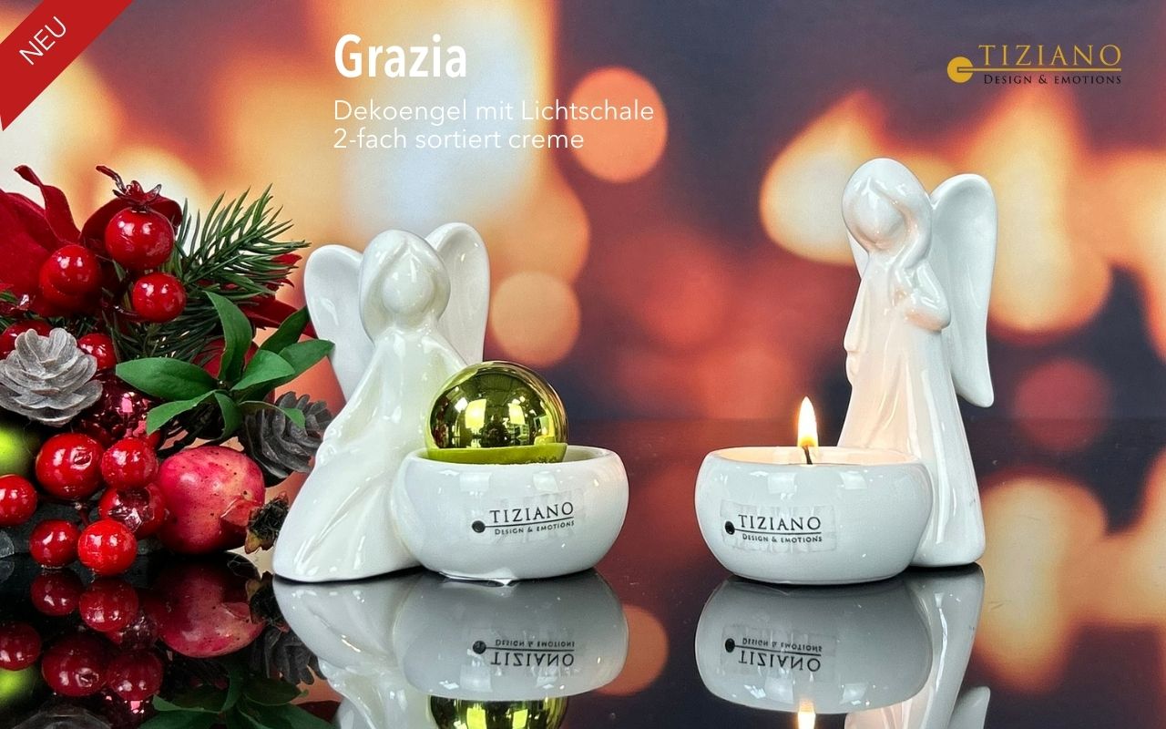 Zwei Engelsfiguren aus weißer Keramik mit integrierten Kerzenhaltern von Tiziano, eine mit einer goldenen Kugel und die andere mit einem brennenden Teelicht, präsentiert mit festlichen roten Beeren und Grün vor einem verschwommenen, warmen Bokeh-Hint